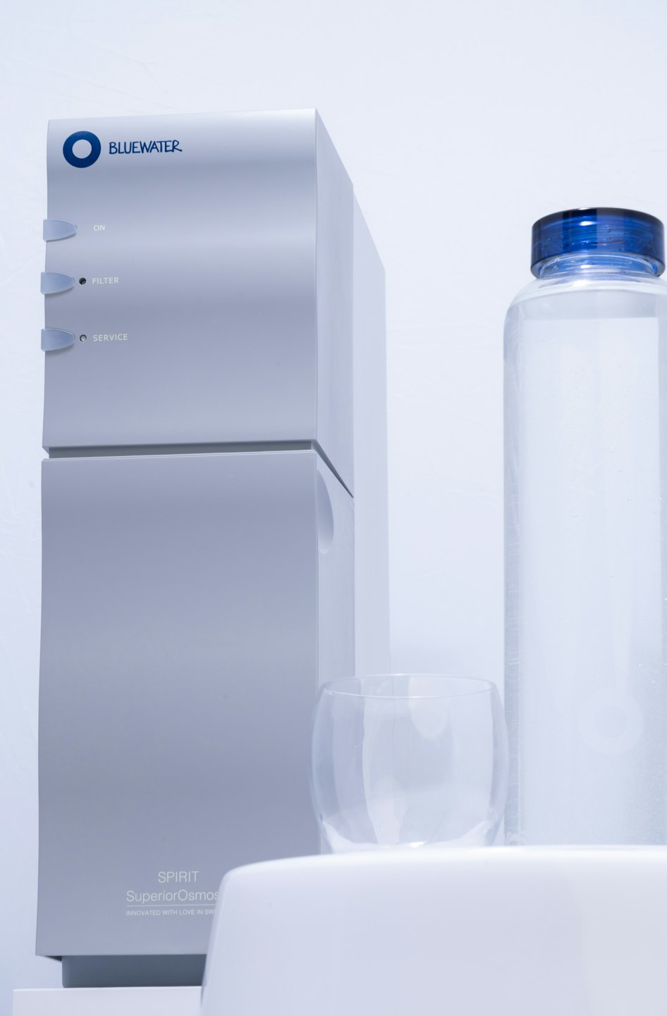 Modern silver water filter with bottle and glass.